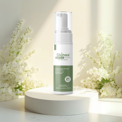 Skinaa Anti Acne Facewash skincare product on a white pedestal with flowers in the background
