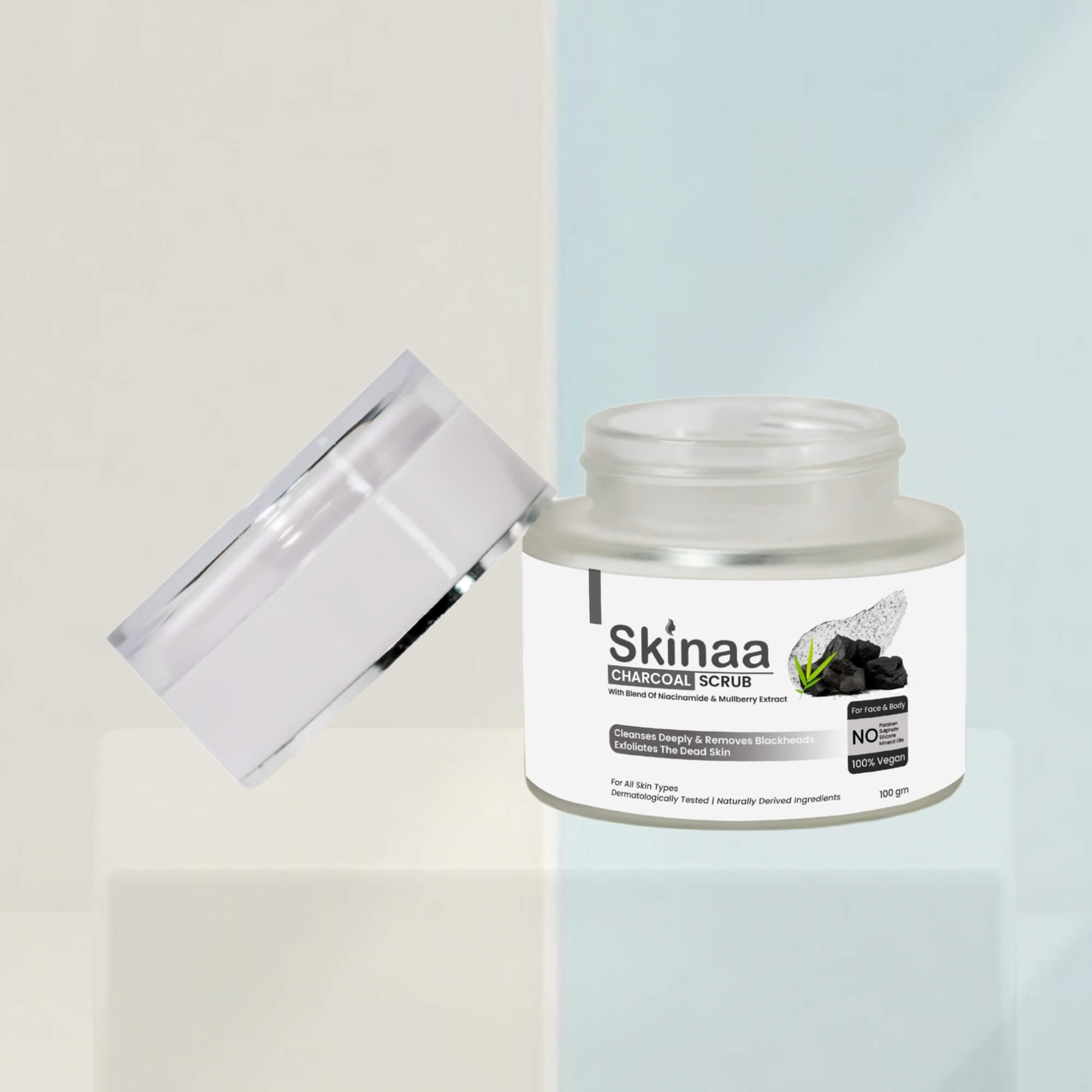 Skinaa Charcoal Scrub jar with open lid, displayed on a minimal background. The exfoliating scrub is formulated for deep cleansing, detoxifying, and smooth skin